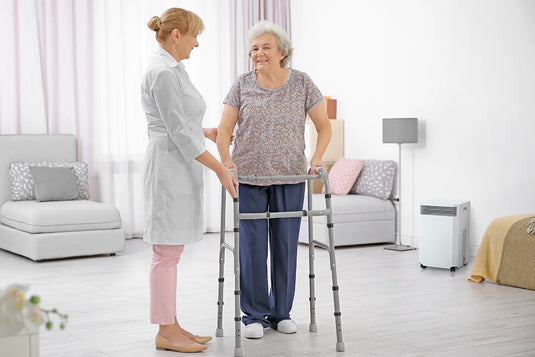 elderly lady with walker smiles at caretaker with INOVA air purifier nearby