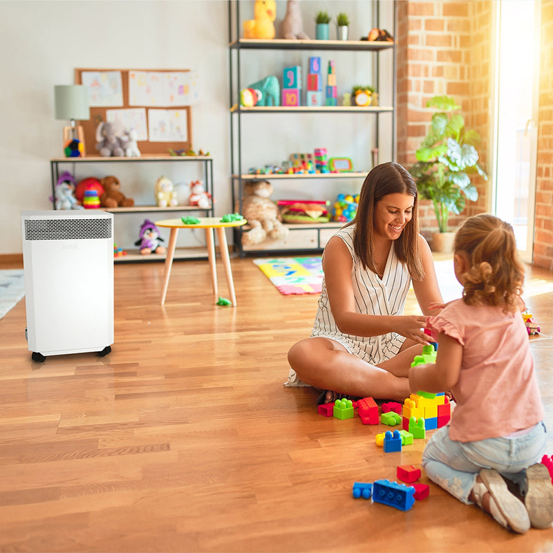 Load image into Gallery viewer, A children&#39;s playroom where a young woman plays with brightly coloured blocks, entertaining a small child. In the background, an INOVA air purifier quietly cleans the air, removing harmful dust particles, viruses and bacteria.
